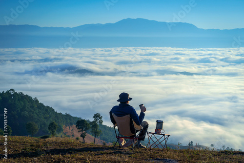 Asian Man is happy and relaxed with the scenery of the sea mist a beautiful natural in the morning at Car Camping site on the top of a mountain in winter season at Chiang Mai, Thailand.