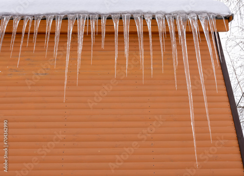 Huge icicles hang from the roof of a building with an orange facade
