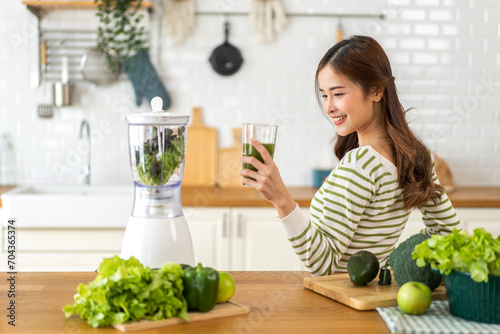 Portrait beauty healthy asian woman making green vegetables detox cleanse and green fruit smoothie with blender.young girl drinking glass of green fruit smoothie in kitchen.Diet concept.healthy drink