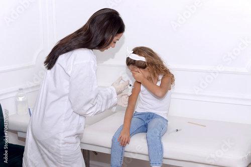 Vaccine fear in children, Little girl in face mask in doctor's office is vaccinated. Crying, scared, afraid of syringe with vaccine coronavirus ,flu, infectious diseases .Clinical trials of injection