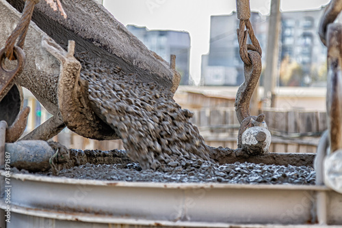 Photos concrete from a concrete mixer is poured onto a construction site