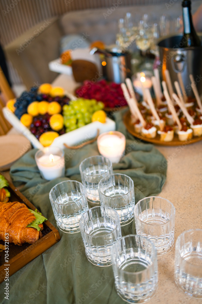 Swiss table at the party. Close up of croissants with greens and glasses with drinks Swiss table at the party. Close up of croissants with greens and glasses with drinks