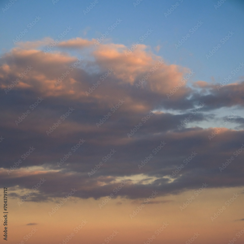 A serene sky with gentle clouds, illuminated by the fading sunlight.