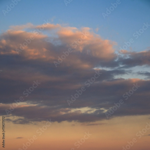 A serene sky with gentle clouds, illuminated by the fading sunlight.