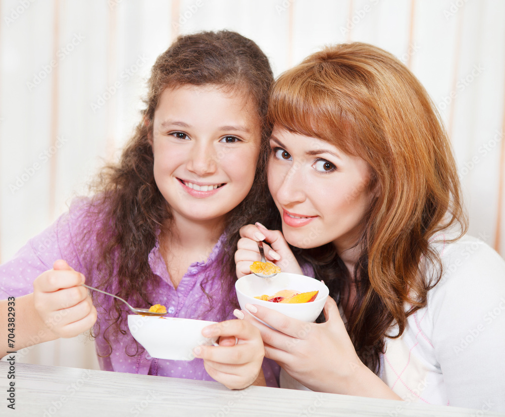 Mother and daughter eating cereal and fruit Mother and daughter eating cereal and fruit