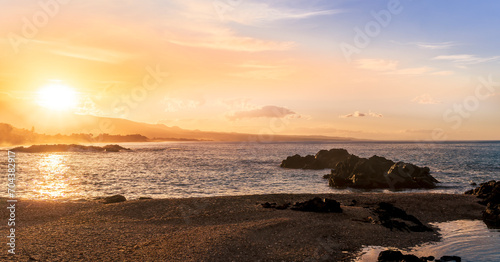 beautiful coast beach with sea gulf water during sunset or sunrise with golden sand, nice black rocks and stones, colorful vawes and clouds in thr sky