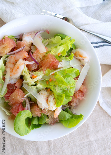 plate with salad with pomelo and shrimp on the table