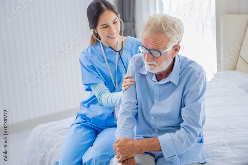 Hospice nurse is using stethoscope on Caucasian man in bed for diagnosing lung cancer and heart rate at pension retirement center for home care rehabilitation and post treatment recovery process photo