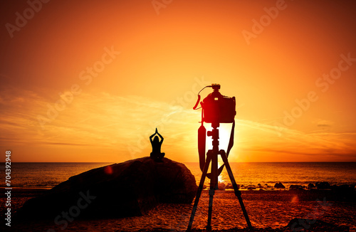 Fotokamera mit Stativ vor einem Sonnenuntergang am Meer