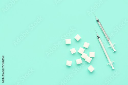 Sugar cubes with syringes for insulin injection on green background