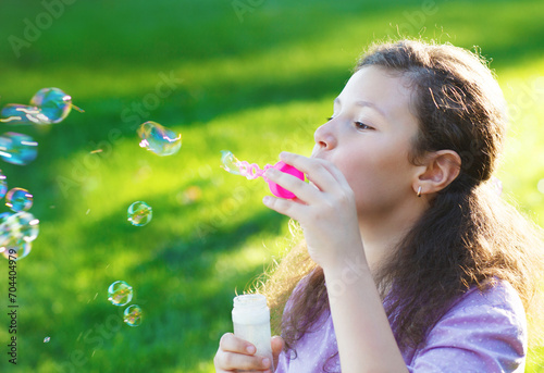 Little cute girl blowing soap bubbles outdoors