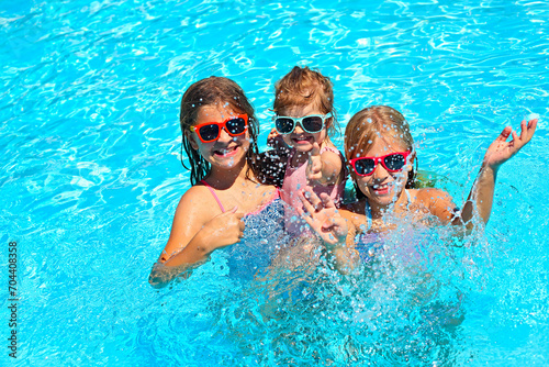 Cute girls playing in swimming pool. Summer vacation and travel concept