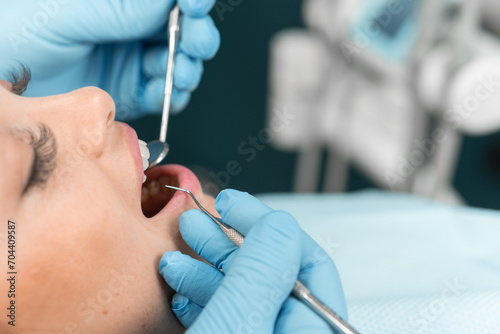 In the dental chair, the patient watches with interest the dentist, who improves her smile. The doctor displays a high level of professionalism and focus on every detail.