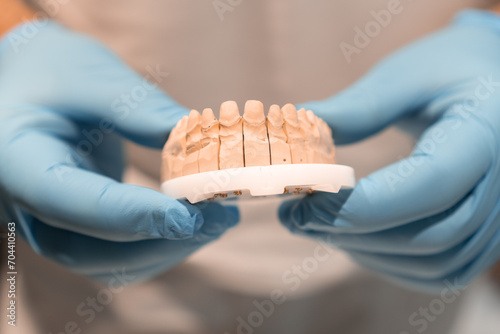 Tooth ingot for further future correction of teeth and taste in a dental clinic. Close-up of tooth ingot held by doctor in gloves photo