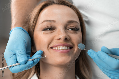 A woman in a dental chair expresses confidence and joy with her flawless smile. The dentist who conducts the appointment monitors her condition with great interest and provides high-quality care.