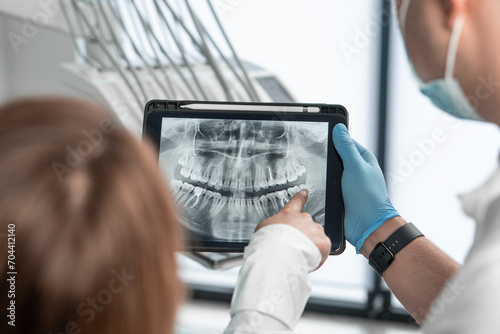 The dentist uses a tablet to visually explain the details of dental treatment so that the patient feels completely confident in her choice. Demonstrates a CT scan, an X-ray photograph photo
