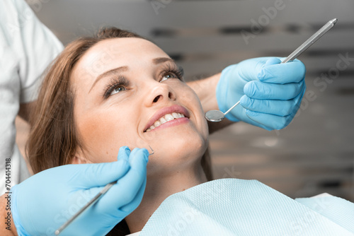 The patient expresses her satisfaction with a smile while sitting in comfortable dental chair. A dentist  choosing an individual approach  makes the procedure as comfortable and effective as possible.