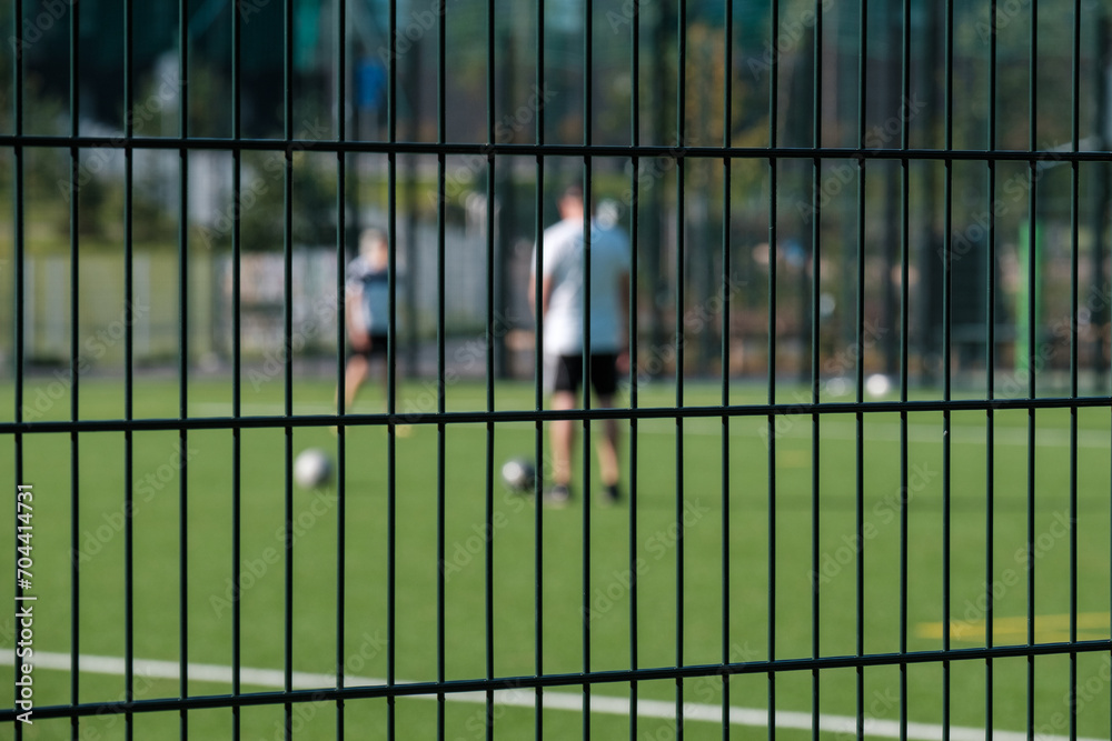 Obraz premium Two unfocused silhouettes of adult males playing soccer in the field.