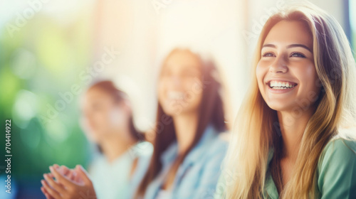 A group of young women smiling and clapping  enjoying a lecture in a bright  sunlit educational setting.