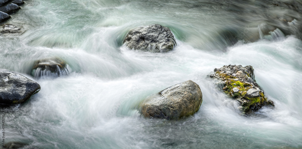 Obraz na plátně Fresh flowing water around boulders ina creek in the Yellowstone National Park,