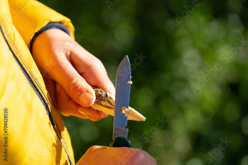 Photography Boy peeling a stick with a razor