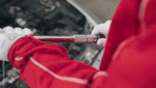 Mechanic adjusting torque wrench in car service to tighten bolts after replacing engine photo