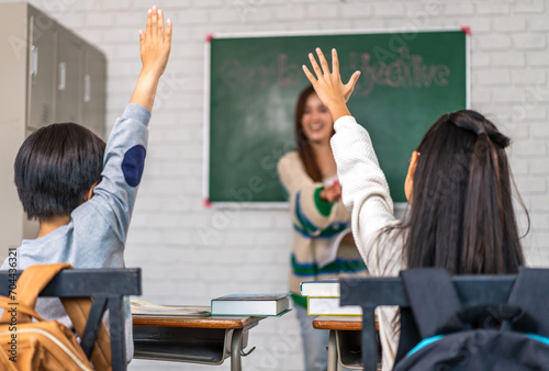 Portrait asian teacher teaching and children student raising hands for question, activity learn, study with book, student, education, knowledge, elementary, lessons, kid, child, in classroom at school photo