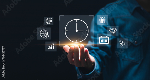 Time management concept. Businessman holding virtual time management icons for business to work planning for increases efficiency and reduced work time. Business project planning.