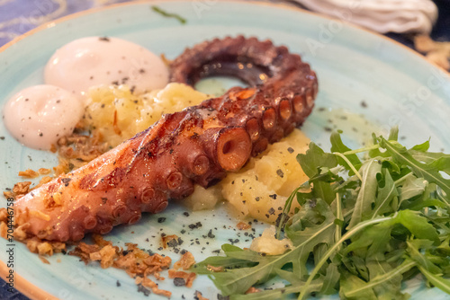 Delicious grilled octopus tentacle, accompanied by salad.  photo