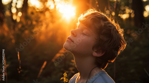 Portrait of a boy with closed eyes in the forest at sunset © Faith Stock