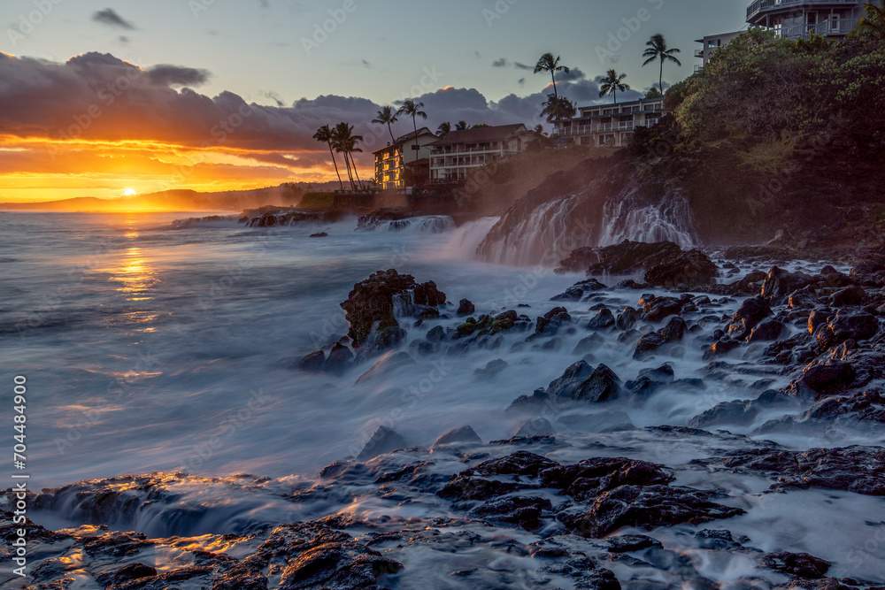 A strong wave action pushed seawater way up on the rocks and the draining back creates an interesting motion feeling as the sun is setting over the ocean, Poipu, Kauai A strong wave action pushed seawater way up on the rocks and the draining back creates an interesting motion feeling as the sun is setting over the ocean, Poipu, Kauai