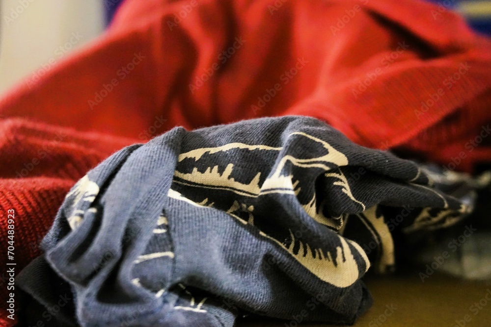 Blaugraues Baumwolltuch mit weißem Muster liegt vor rotem Pullover auf Ablage in Raum Blaugraues Baumwolltuch mit weißem Muster liegt vor rotem Pullover auf Ablage in Raum
