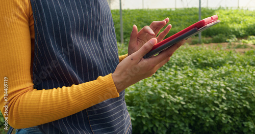 Close up of woman's hands using digital tablet on farm, greenhouse tunnels © Meeko Media