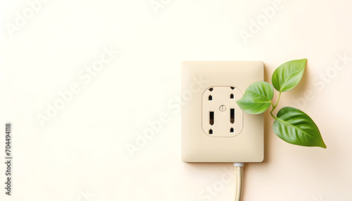 Green outlet or wall socket and power cord with fresh leaves top view. Renewable and saving energy, eco and natural resources concept