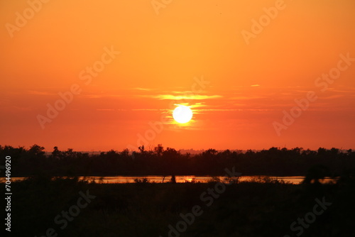 Amanece en el Río Paraná. Como nos tiene acostumbrado en el Litoral argentino, el sol del amanecer pinta tonalidades rojizas durante el alba. photo