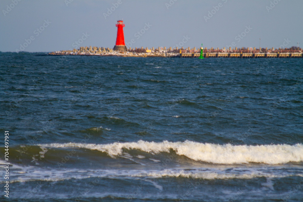 Baltic Sea in winter with a red lighthouse in the foreground.