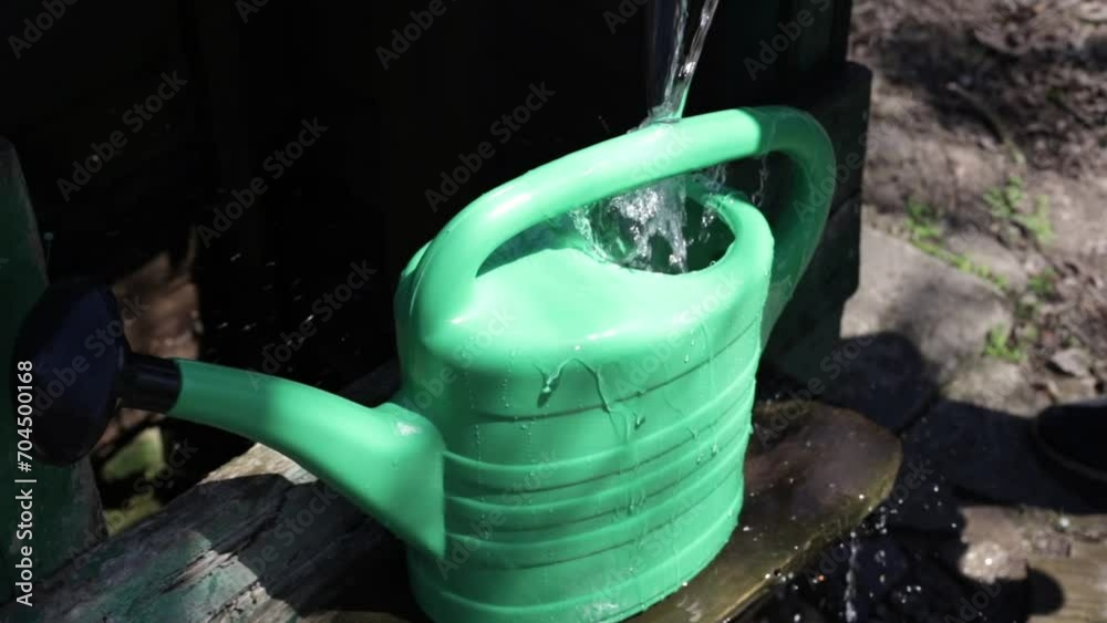 Close up male hands pour water from a well from a bucket into a watering can for watering the ground of flowers plants harvest Close up male hands pour water from a well from a bucket into a watering can for watering the ground of flowers plants harvest