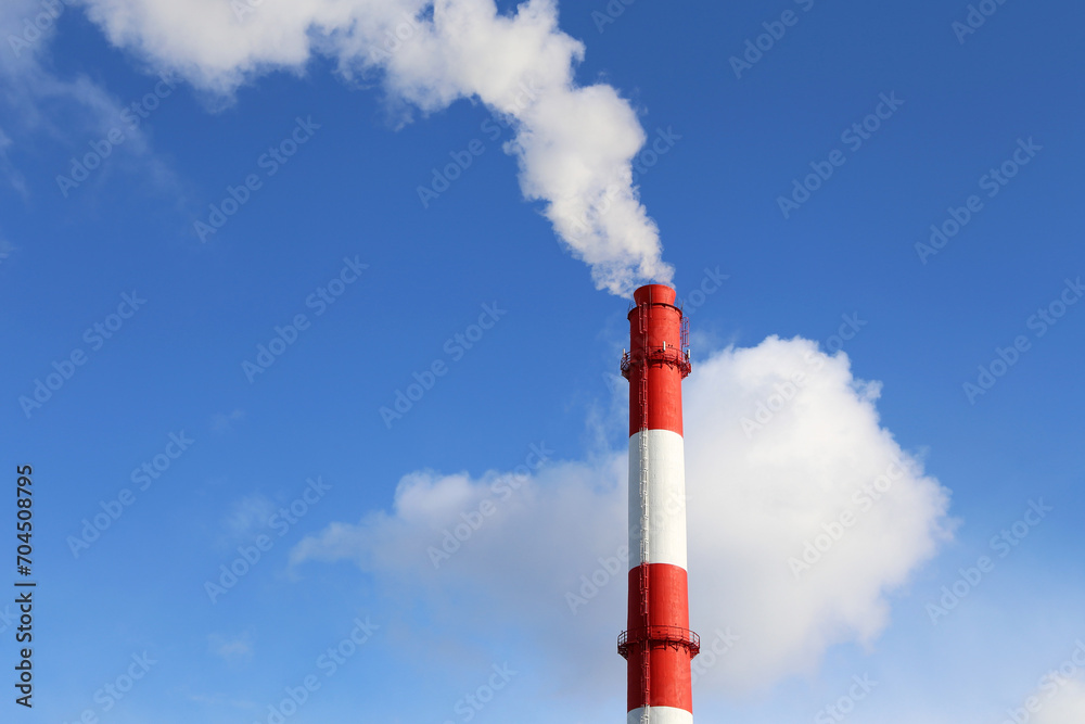 Factory chimney on blue sky and clouds background with white smoke. Concept of steam plant, air pollution, heating season Factory chimney on blue sky and clouds background with white smoke. Concept of steam plant, air pollution, heating season
