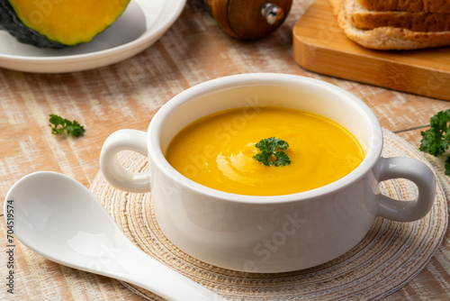 pumpkin carrot cream soup in white bowl,garnished with parsley.Healthy food