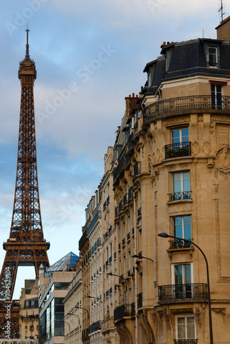 The facade of traditional French house with typical balconies and windows with Eiffel tower in the background . Paris.