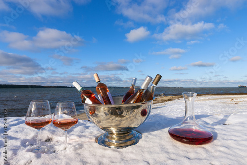 Auswahl an Rosé Weinen im Weinkühler mit gefüllten Weingläsern und Dekanter mit Roséwein.