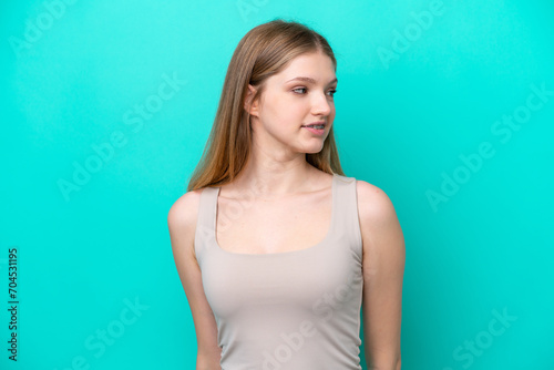 Teenager Russian girl isolated on blue background looking to the side and smiling