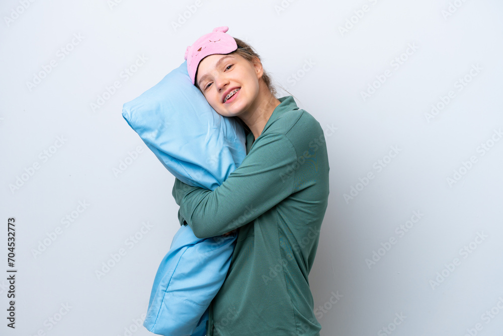 Teenager Russian girl isolated on white background in pajamas and holding a pillow with happy expression Teenager Russian girl isolated on white background in pajamas and holding a pillow with happy expression