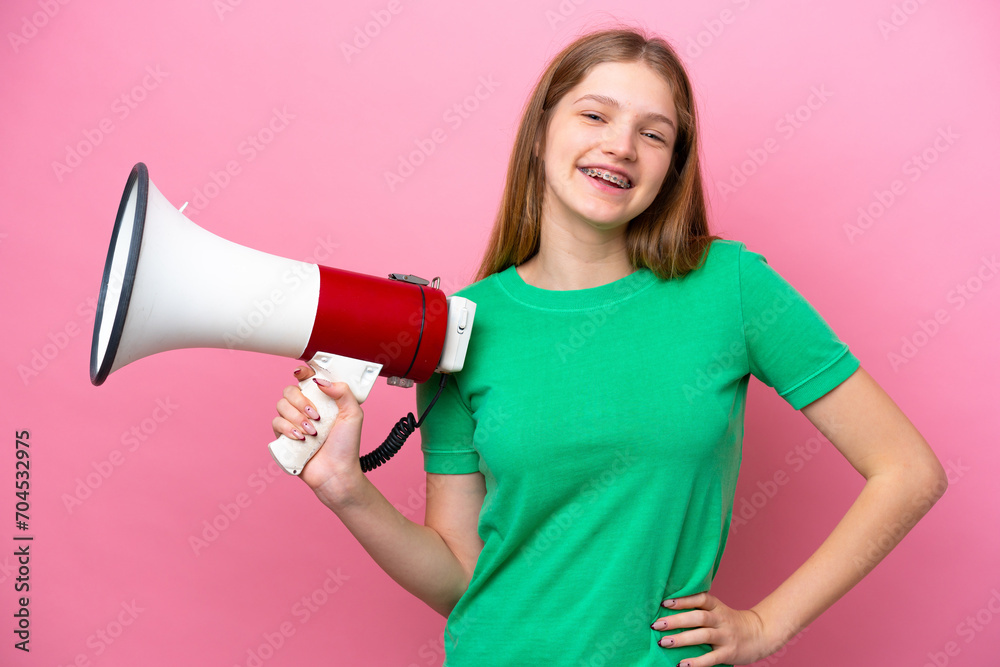 Teenager Russian girl isolated on pink background holding a megaphone and smiling Teenager Russian girl isolated on pink background holding a megaphone and smiling