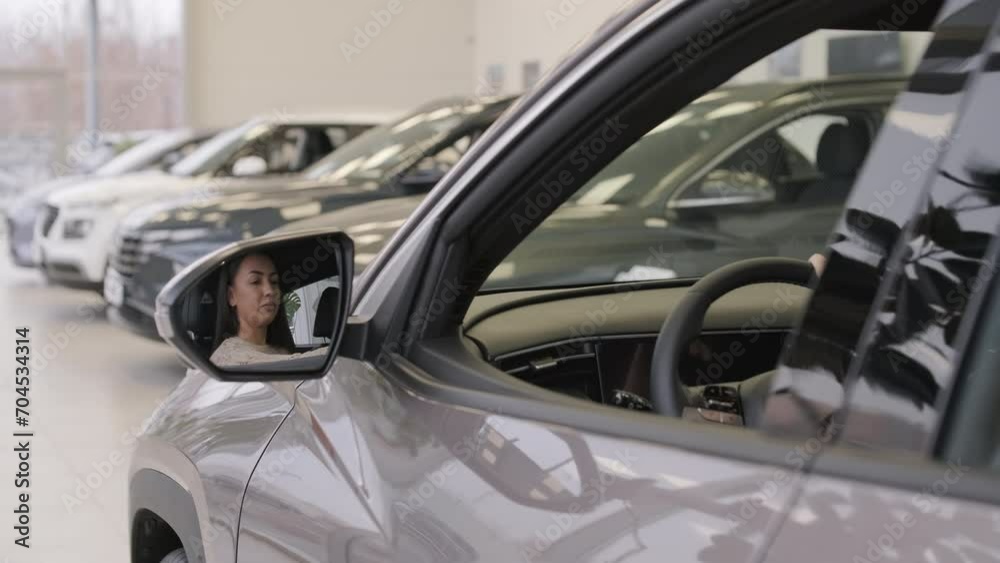 Woman choosing a car in a car showroom Woman choosing a car in a car showroom