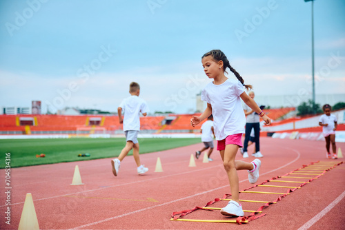 Little girl having PE class on running track at stadium. © Drazen
