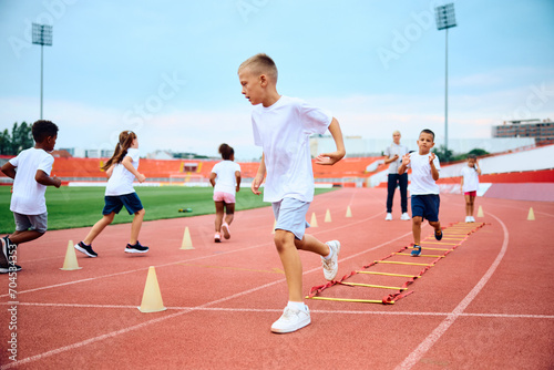 Little boy running during exercise class at stadium.