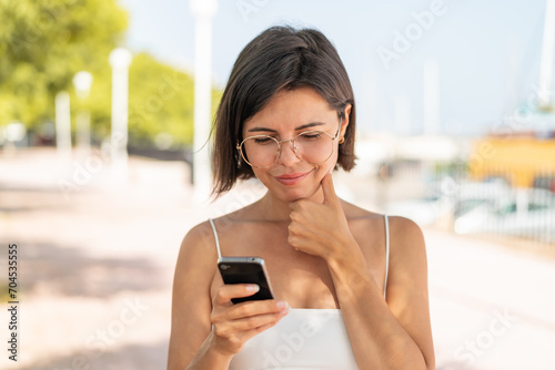 Young pretty Bulgarian woman with glasses at outdoors thinking and sending a message