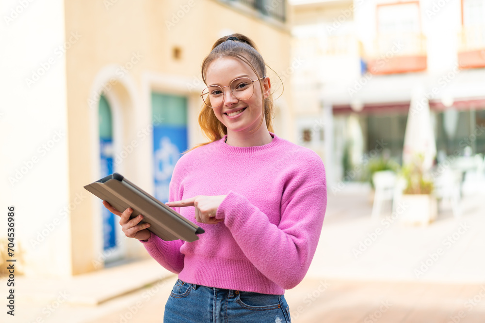 Young pretty girl at outdoors touching the tablet screen with happy expression Young pretty girl at outdoors touching the tablet screen with happy expression