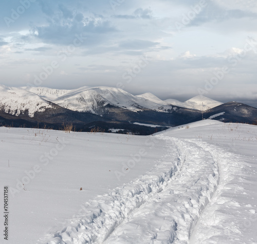 Sledge trace and footprints on winter mountain hill top photo